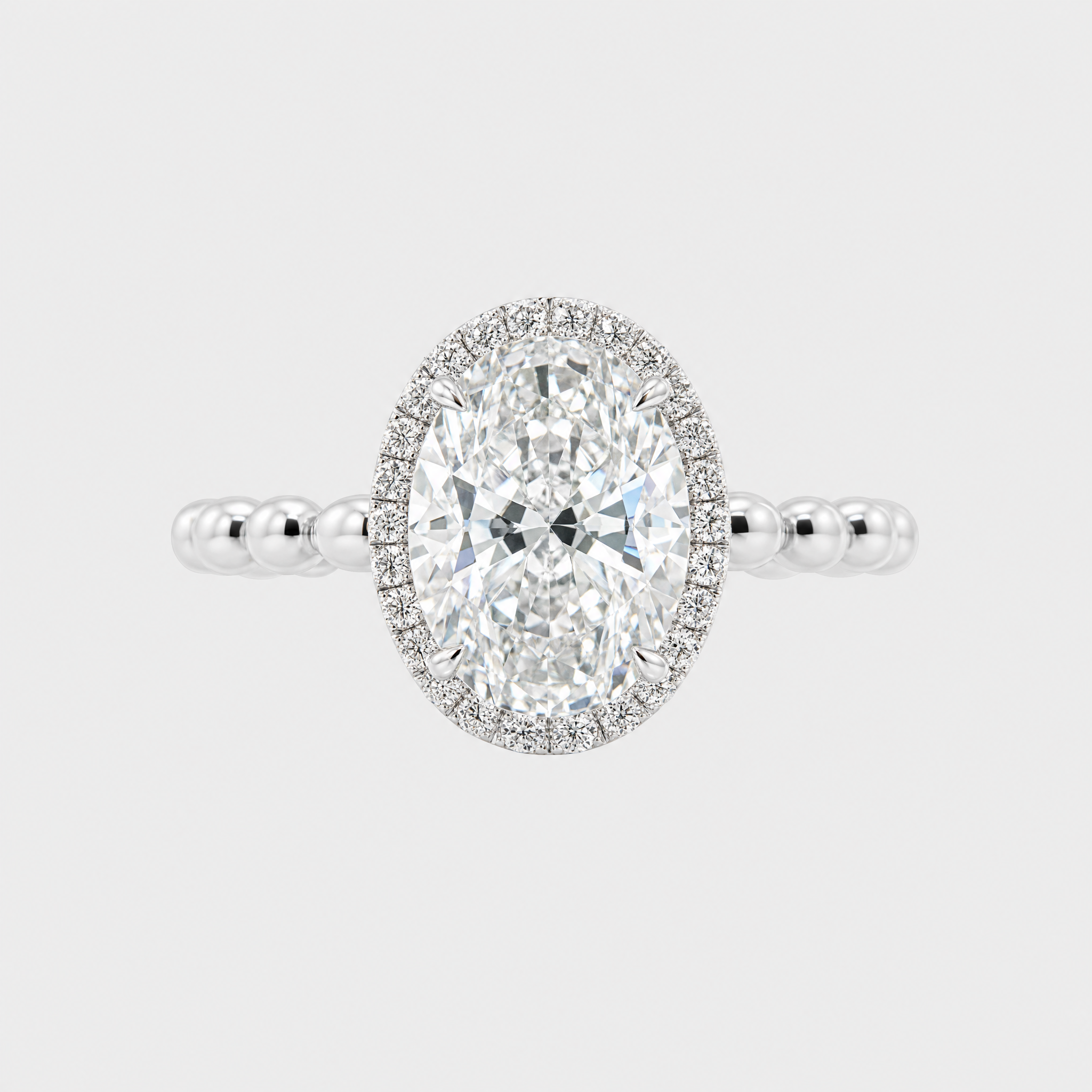 Front view of an oval-cut center stone halo engagement ring with a white-metal beaded band.