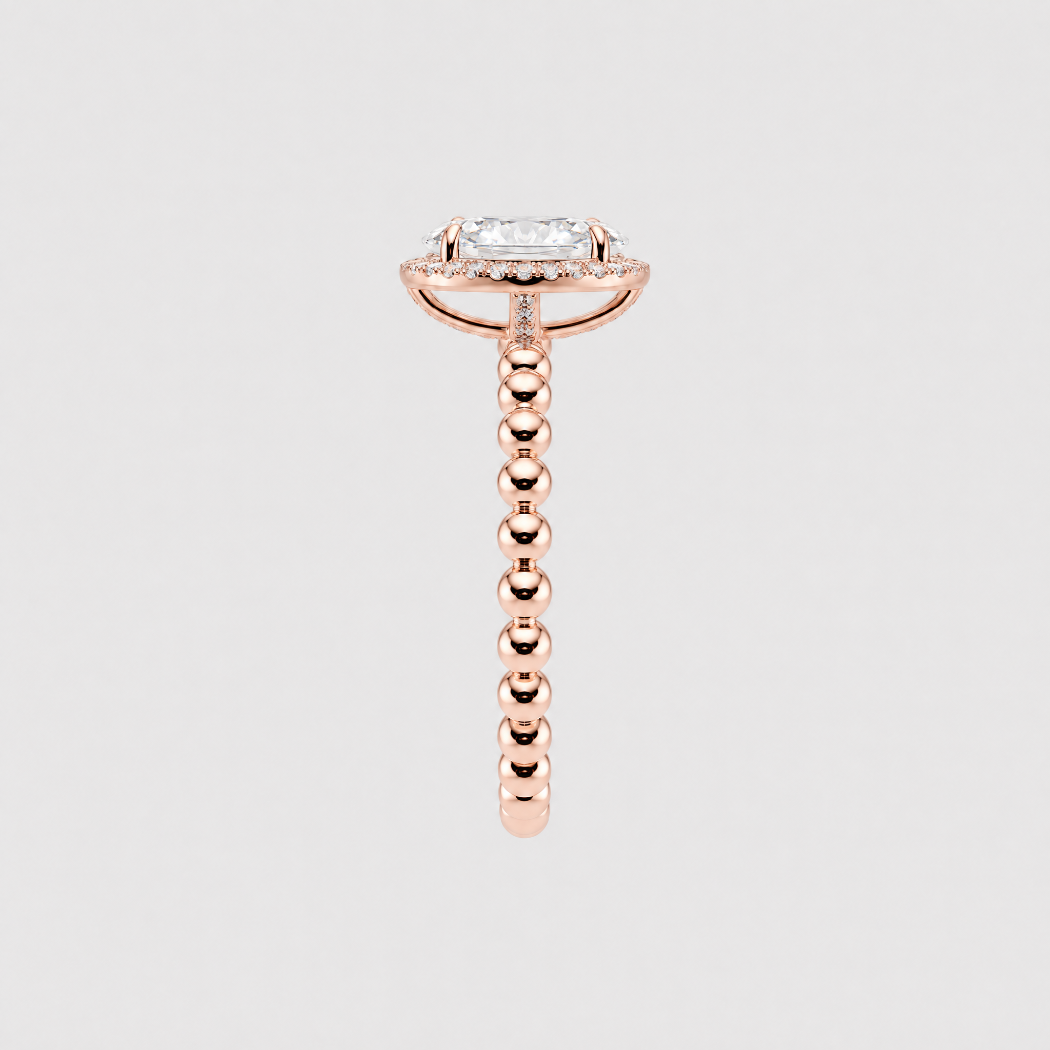 Side profile of an oval halo engagement ring showing the rose gold setting and beaded band.