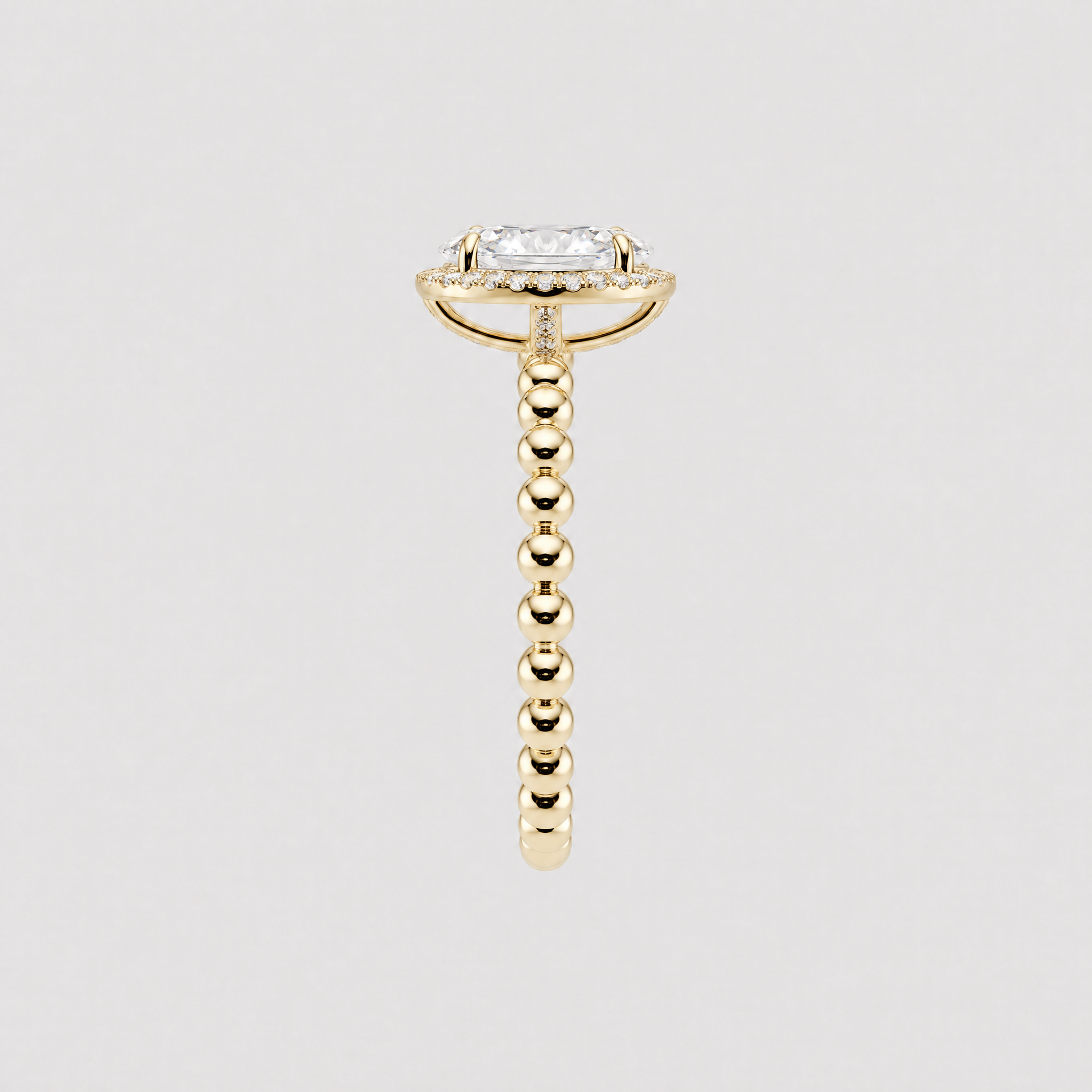 Side profile of an oval halo engagement ring showing the yellow gold setting and beaded band.