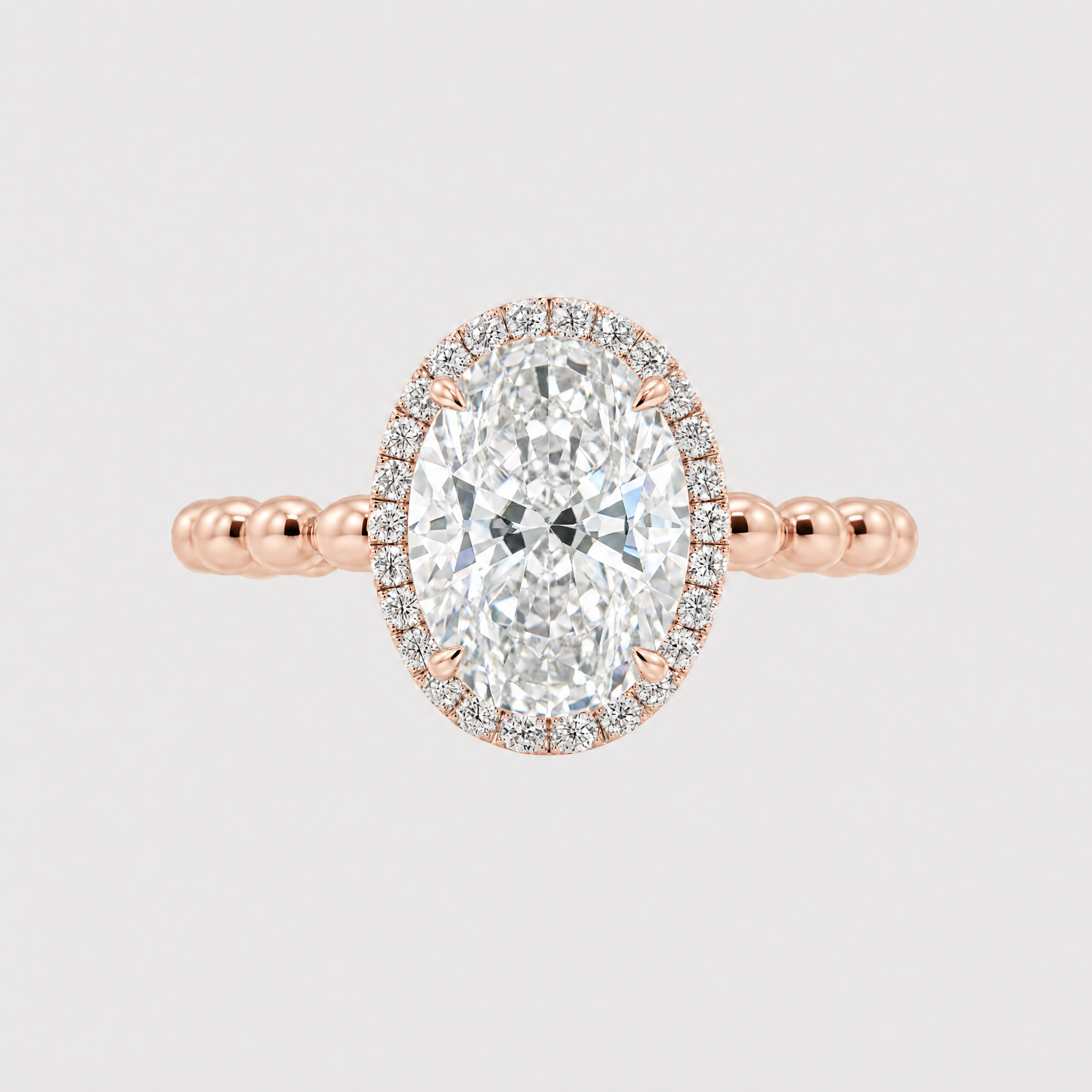 Front view of an oval-cut center stone halo engagement ring with a rose gold beaded band.