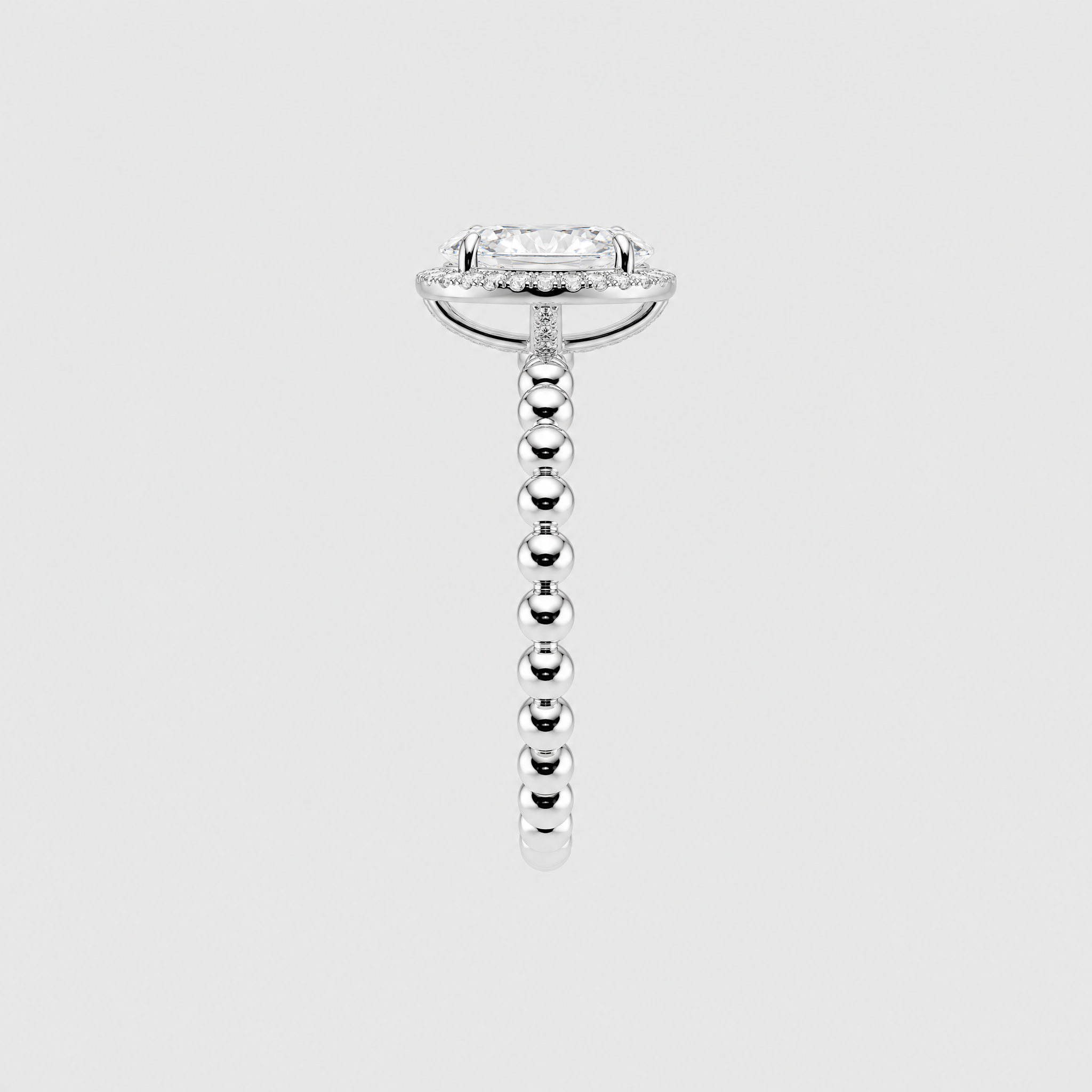 Side profile of an oval halo engagement ring showing the white-metal setting and beaded band.