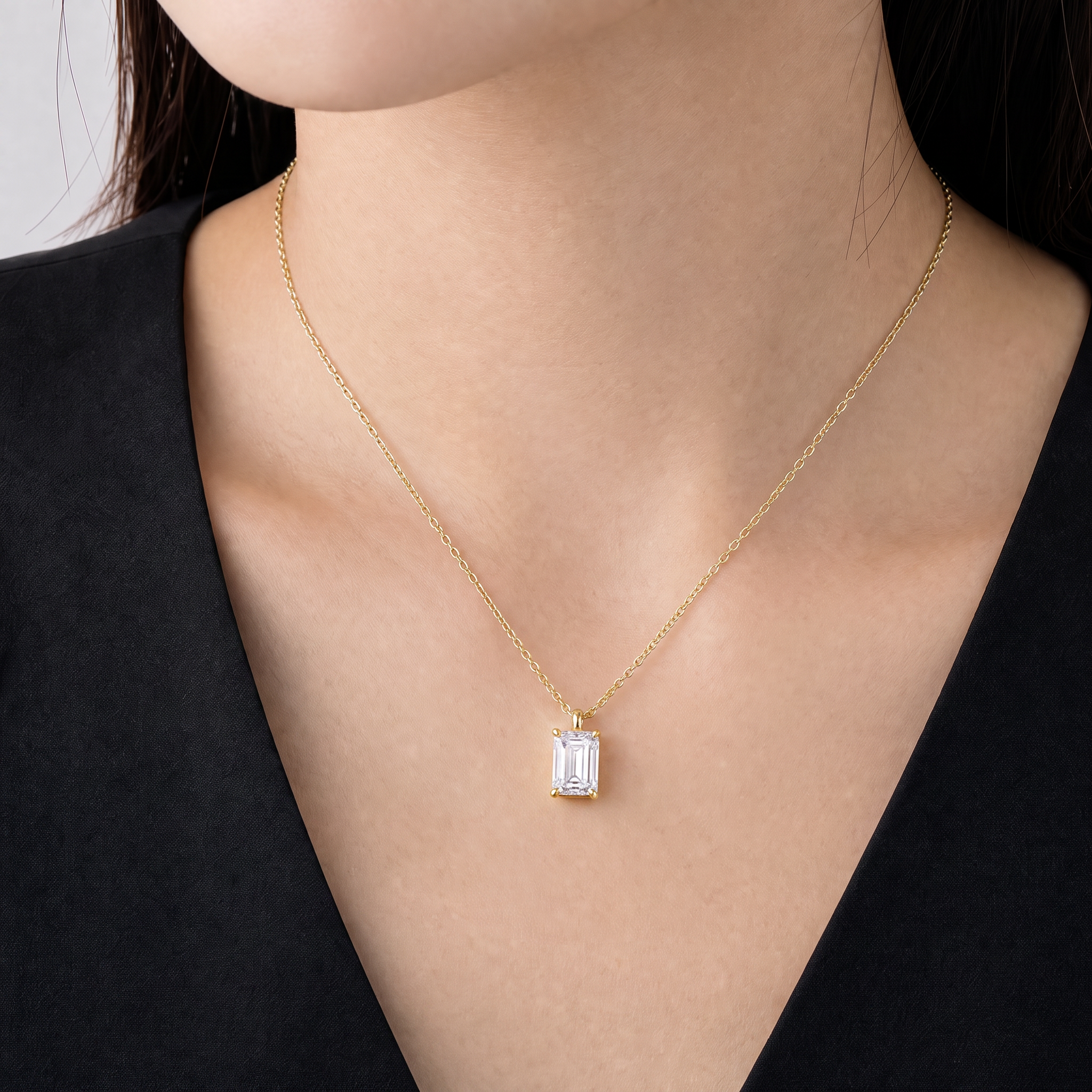 Yellow-gold emerald-cut pendant worn on a fine chain in a close-up neck view.