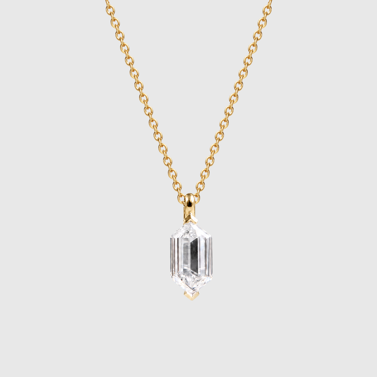 Yellow metal elongated hexagon-cut diamond pendant shown on a chain from the front.
