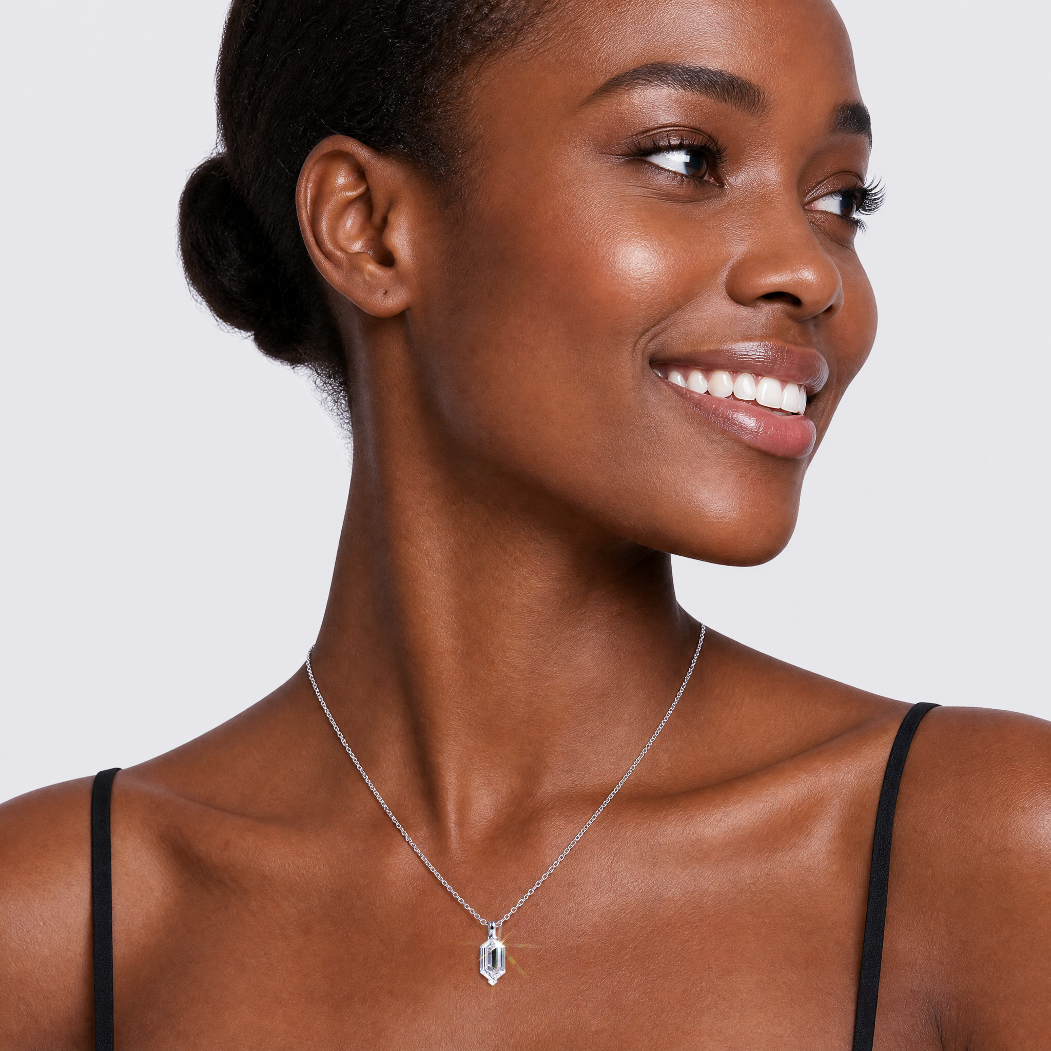 White metal elongated hexagon-cut diamond pendant worn on the neck to show its scale.