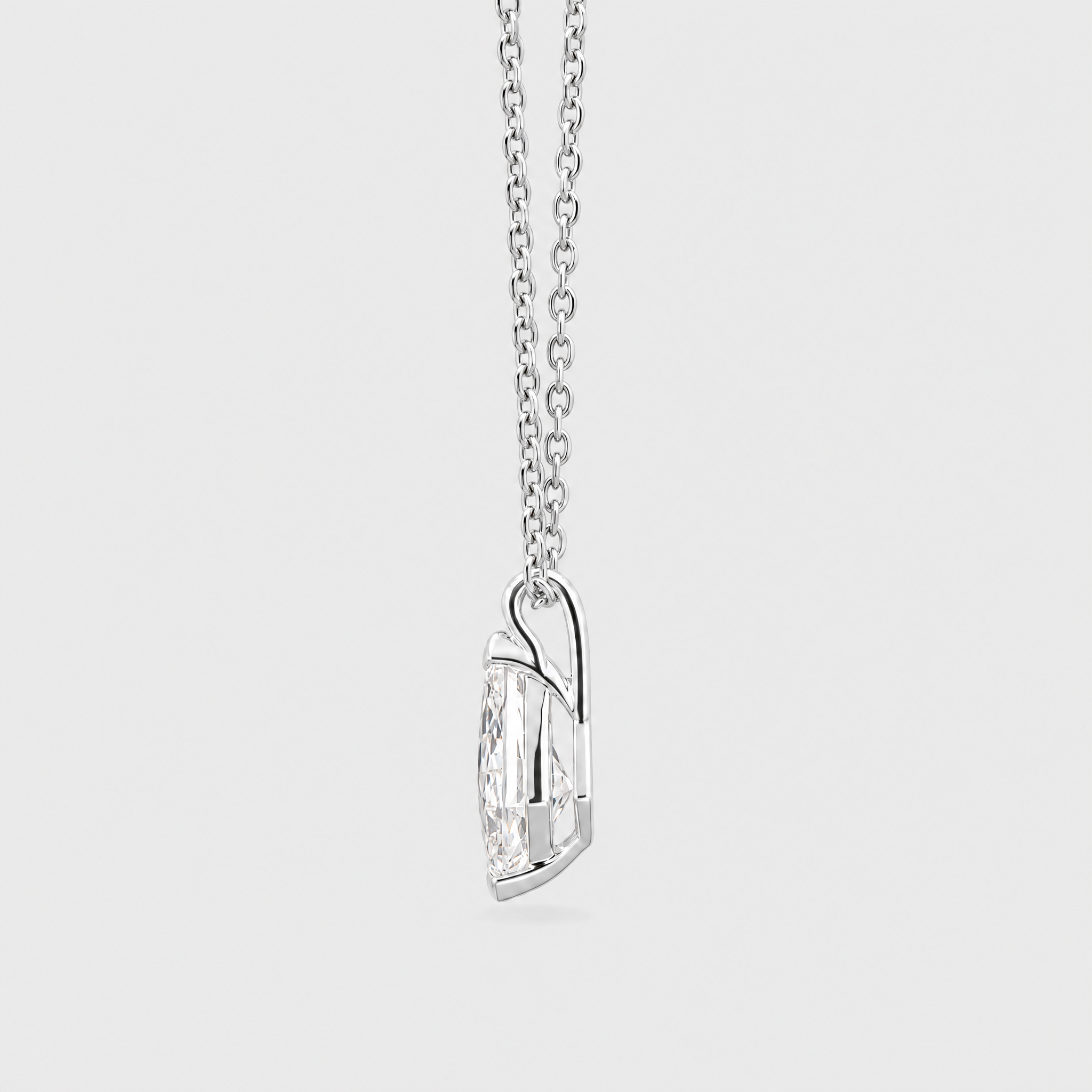 Side view of a kite-cut solitaire pendant in white metal displayed on a matching chain.