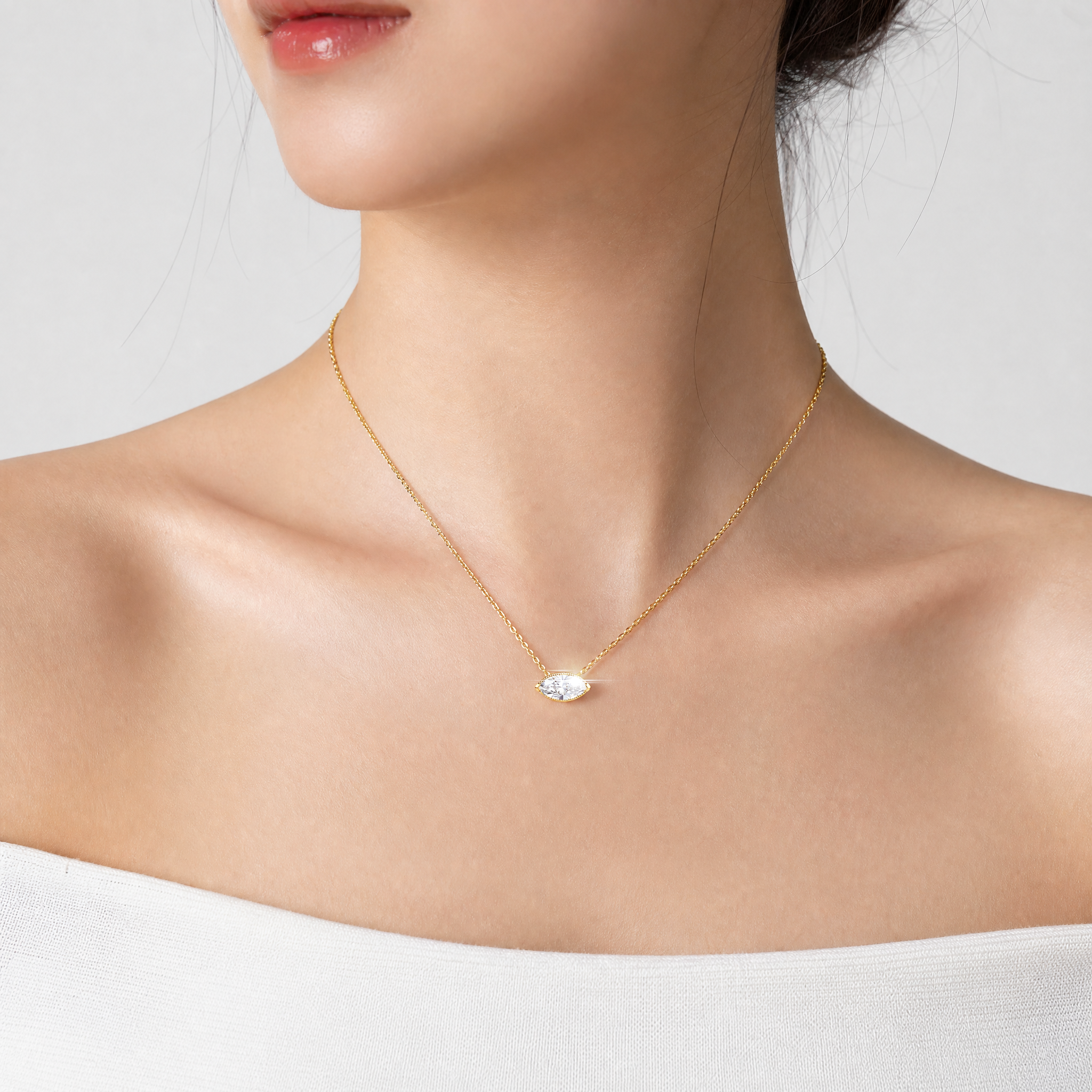 Model wearing a marquise-cut diamond pendant in yellow gold on a fine chain.