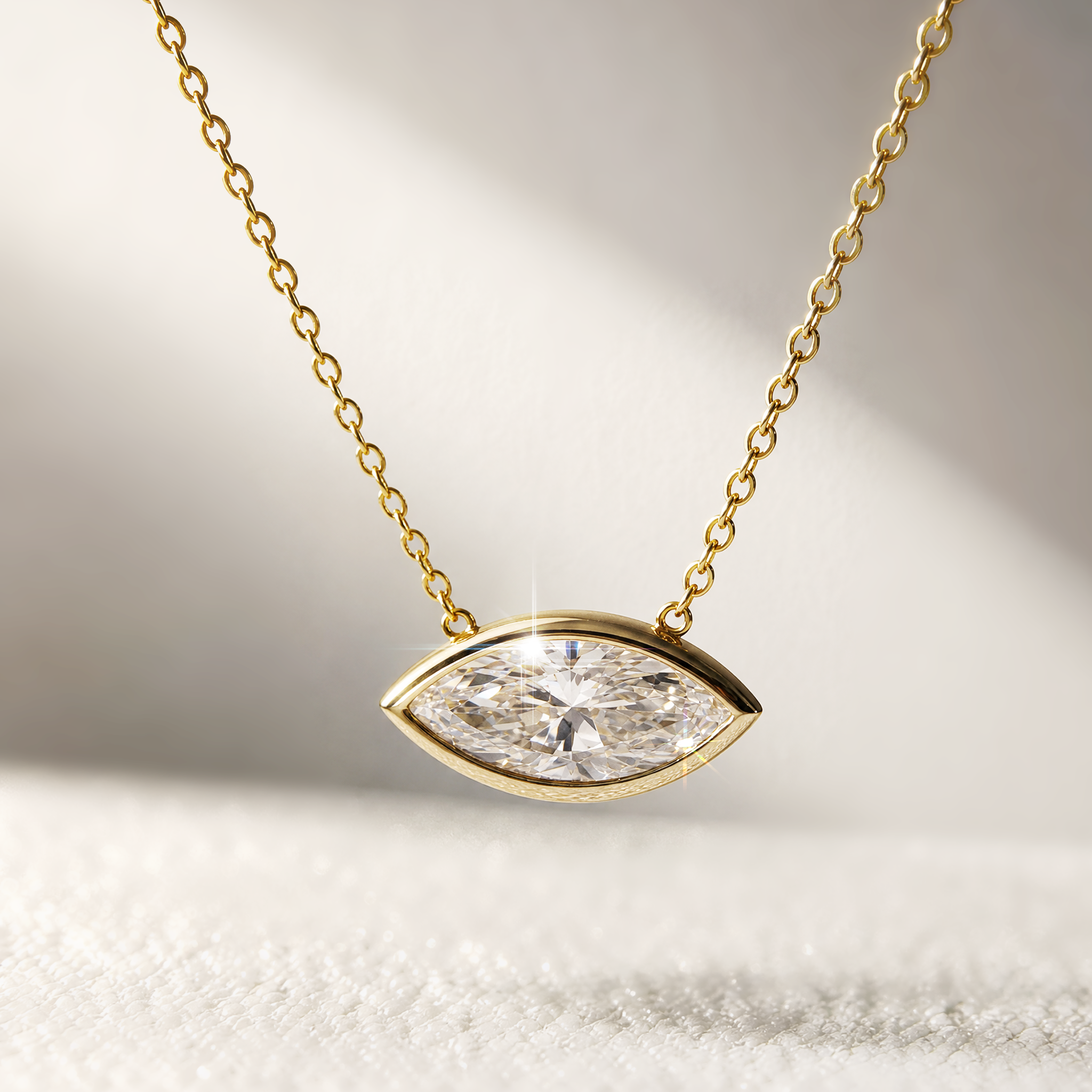 Yellow gold east-west marquise diamond pendant necklace in a styled scene.