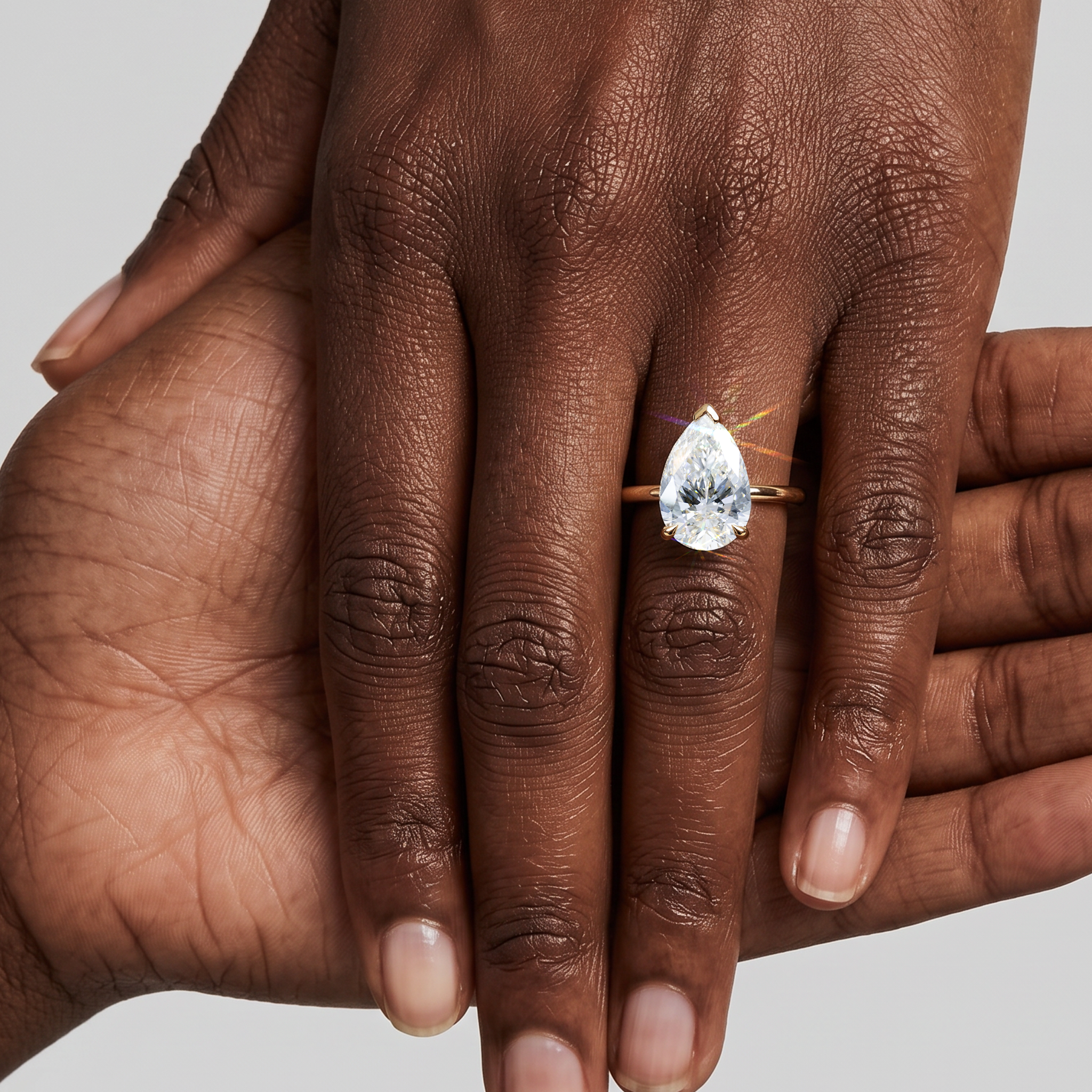 Model wearing a pear-shaped lab-grown diamond solitaire engagement ring in yellow gold.
