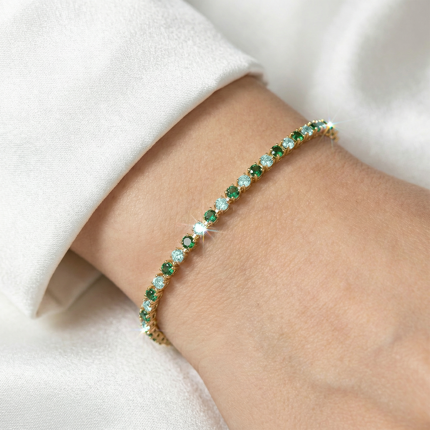Gold bracelet with green gemstones on a wrist against a white background