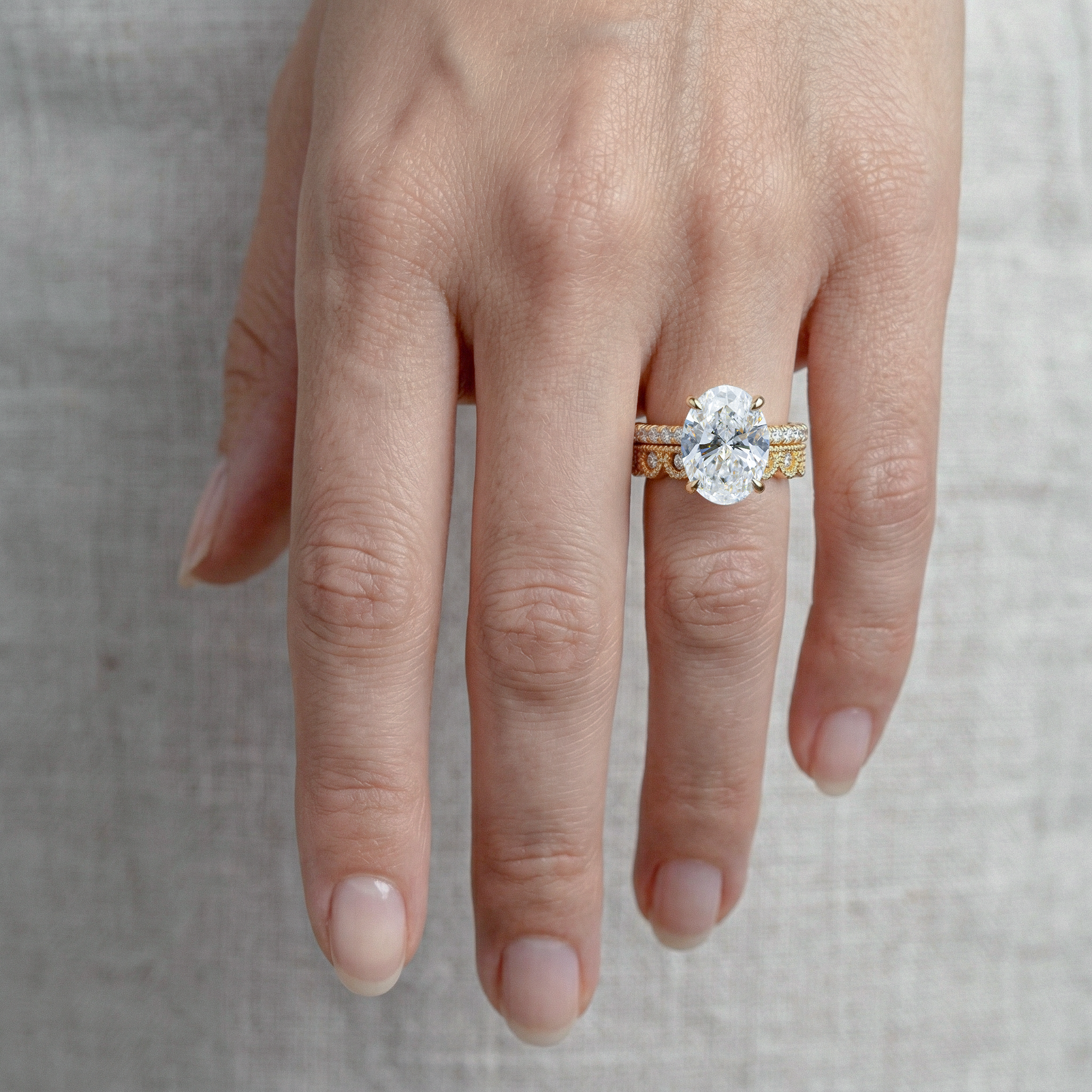 Hand wearing a gold ring with a large oval diamond with vintage band