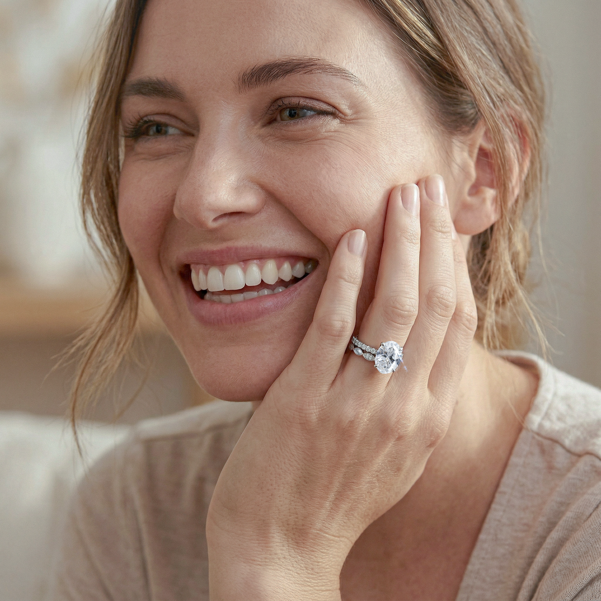 Woman wearing oval diamond  ring set , smiling with hand near face