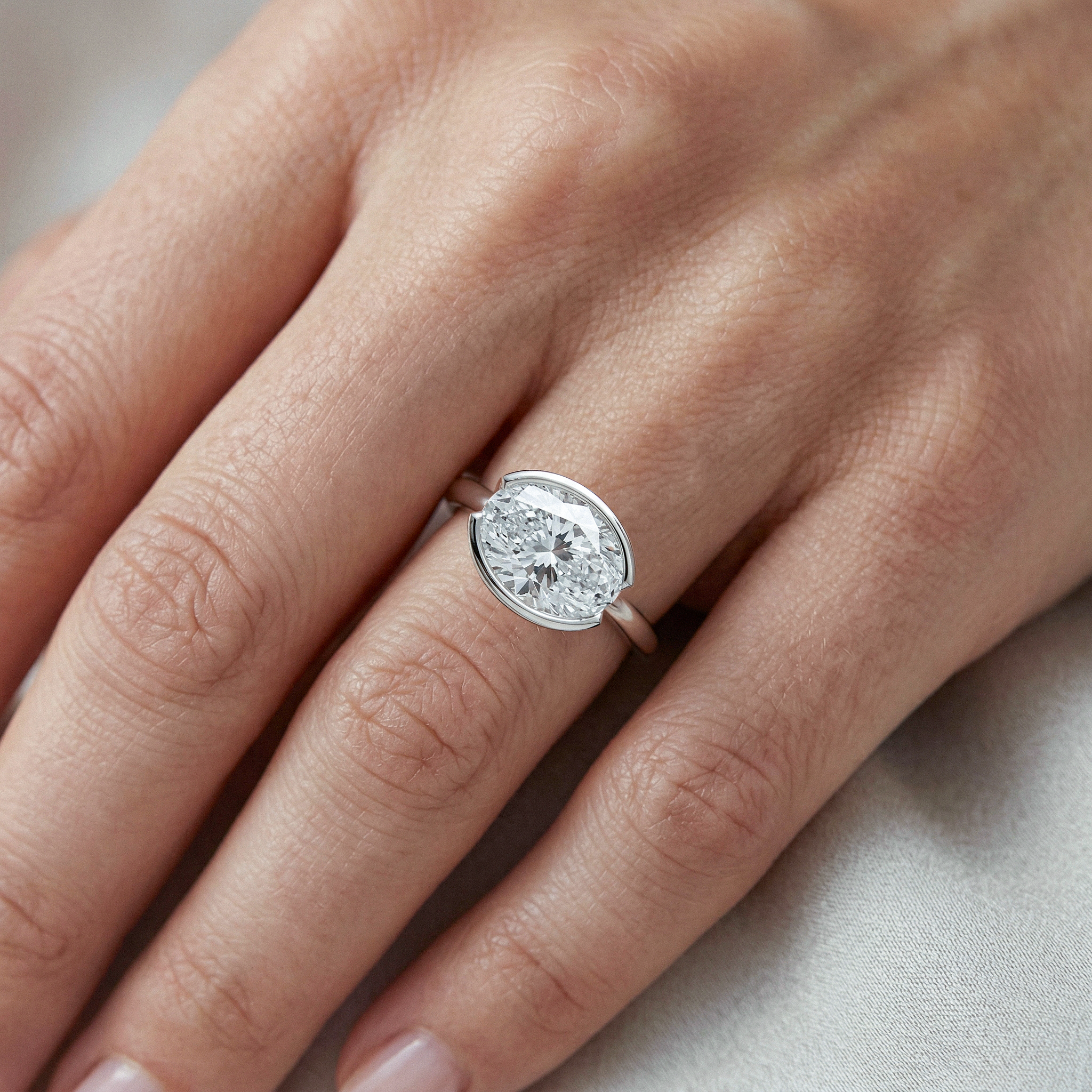 white gold  ring with a oval cut diamond on a person's finger 