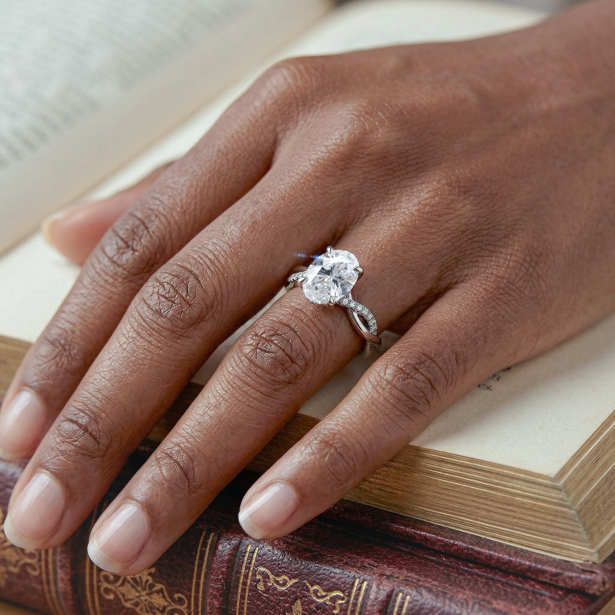 Hand wearing twisted ring with a large oval  diamond  on an open book