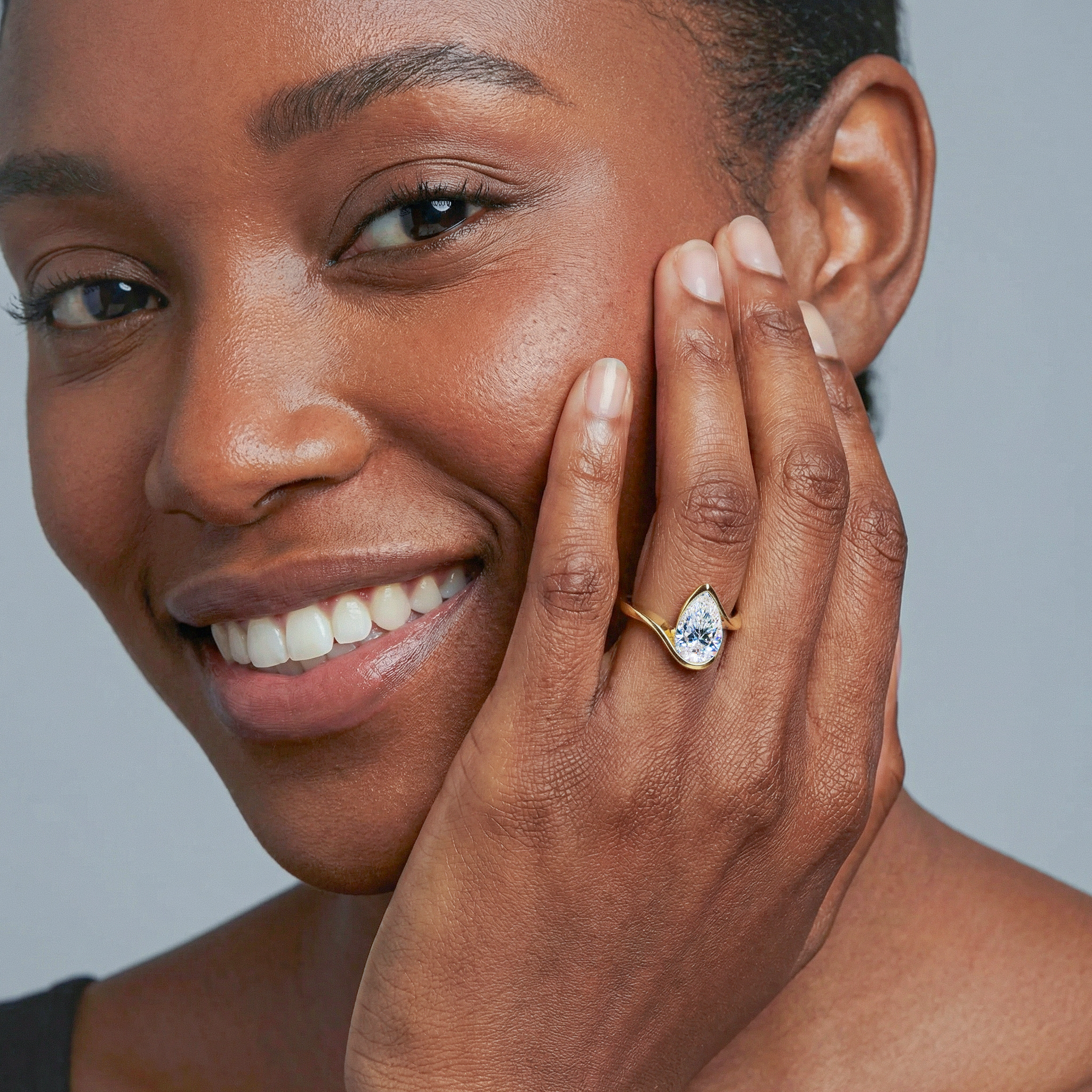 Woman wearing a gold ring with a pear shape diamond twisted band