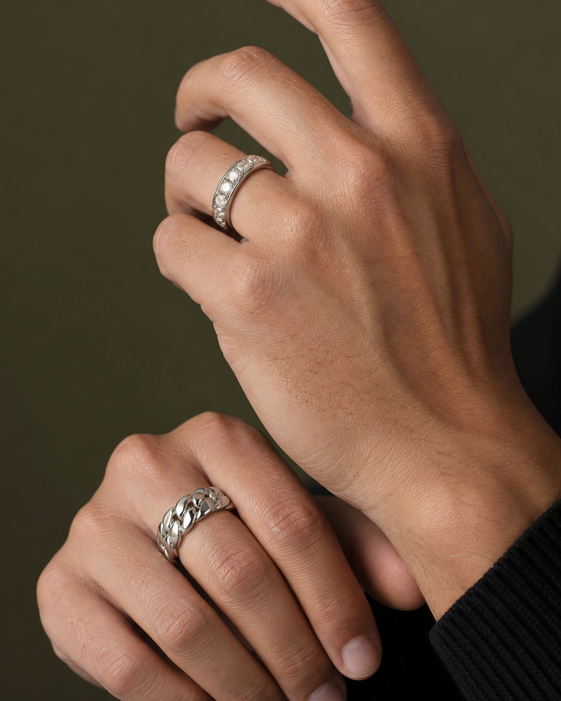 Close-up of two hands wearing white gold rings on a dark background