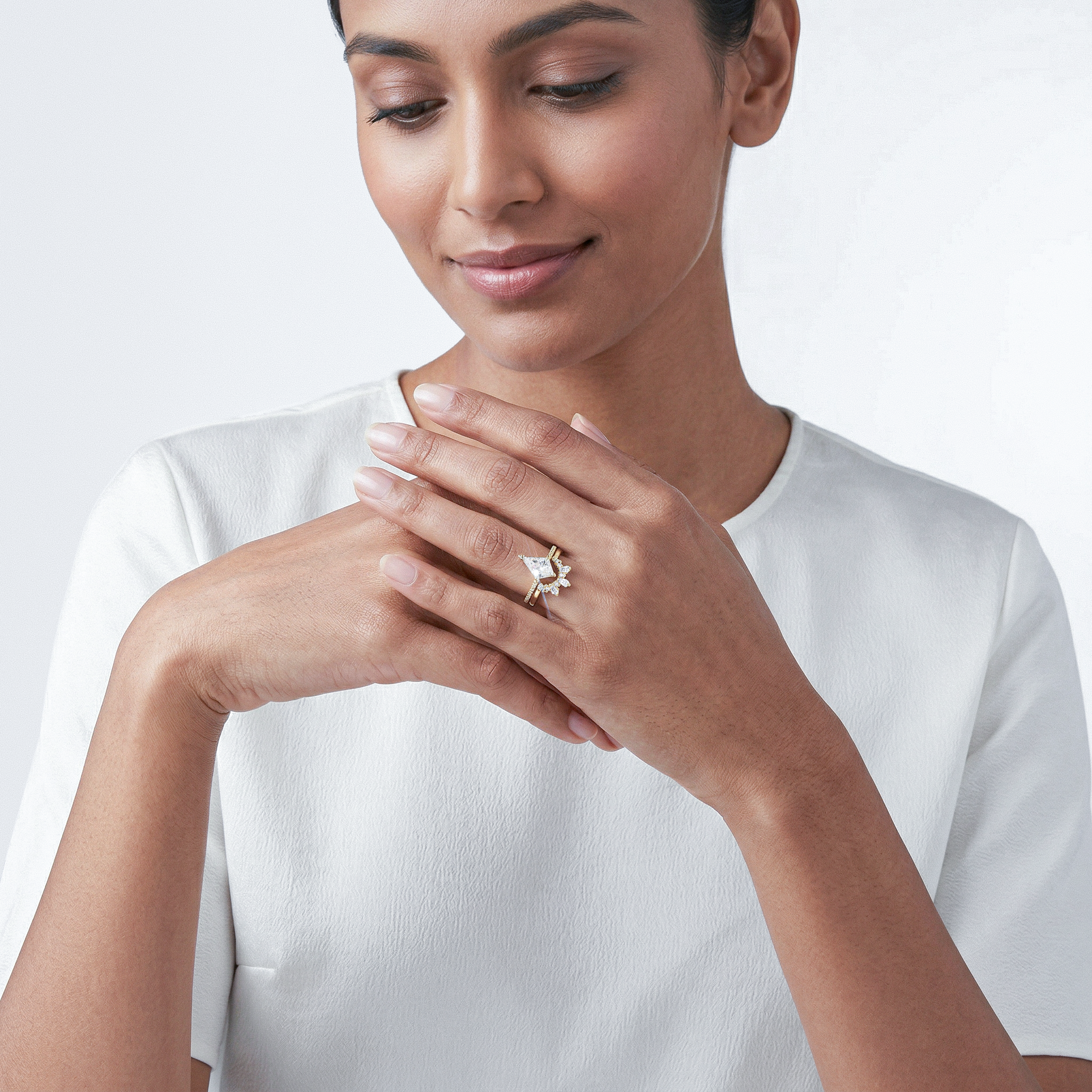 Woman  wearing a white gold kite diamond  ring set on a plain background