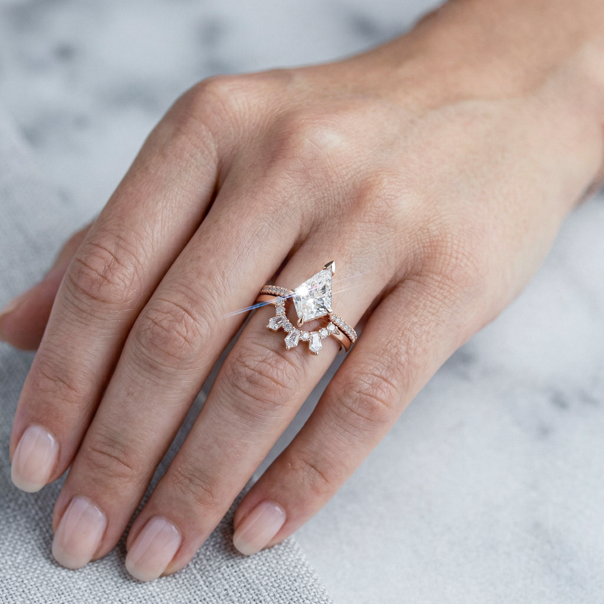 Close-up of a hand wearing a rose gold ring with a diamond on a light background
