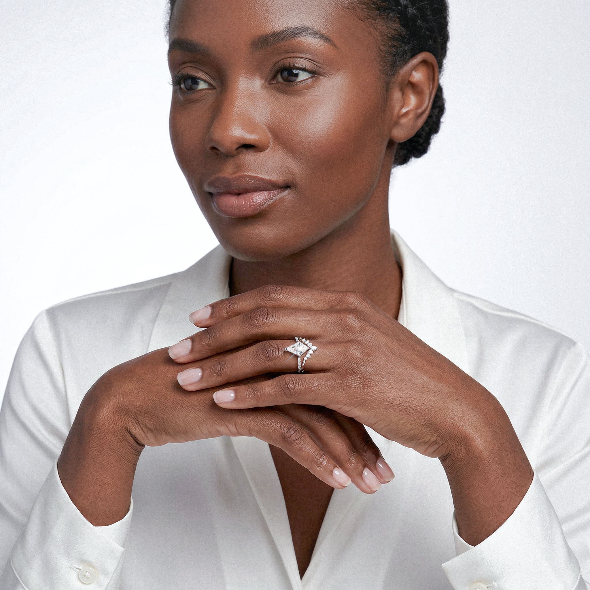Woman wearing a diamond ring with a white shirt on a light background