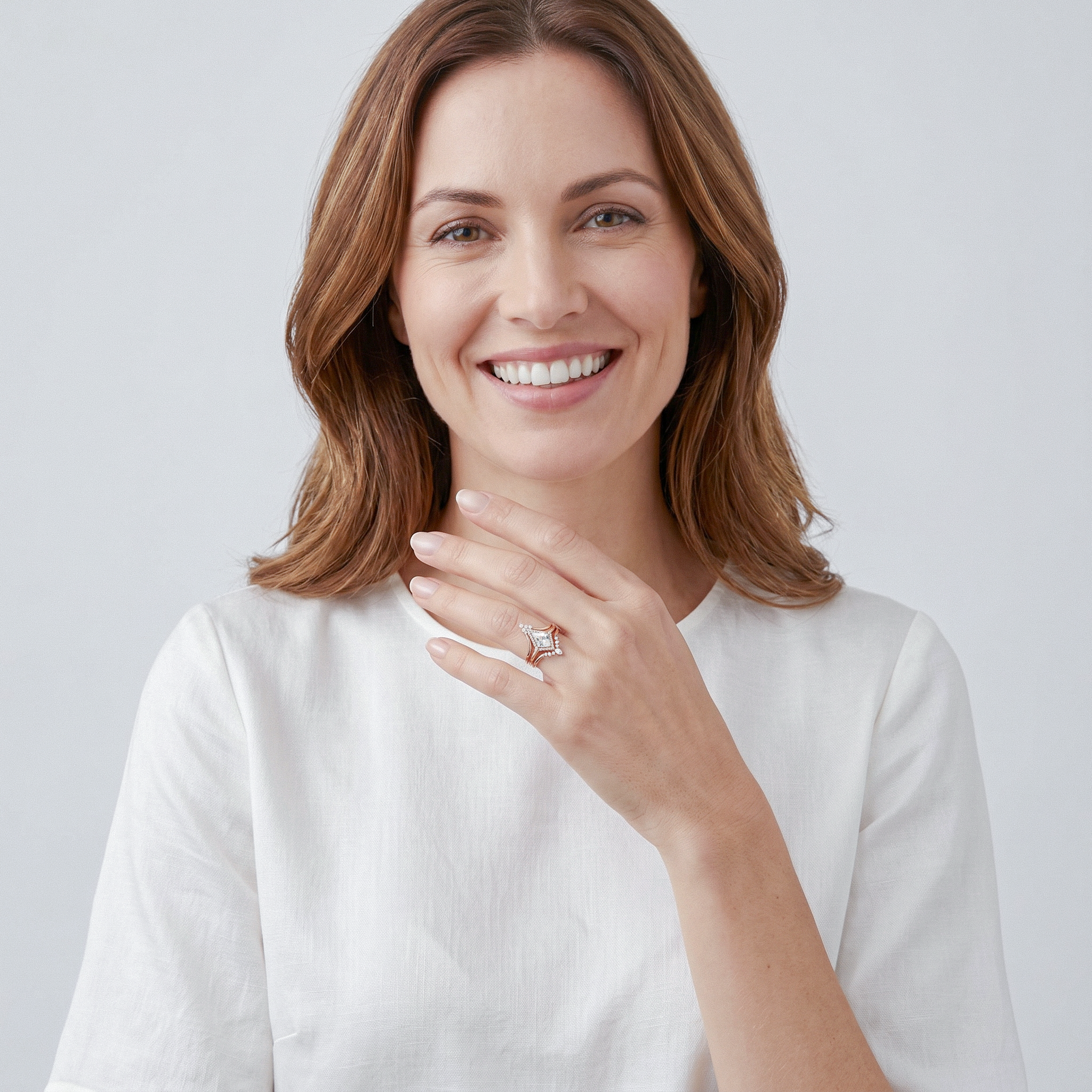 Woman wearing golden halo kite diamond ring set on a plain background