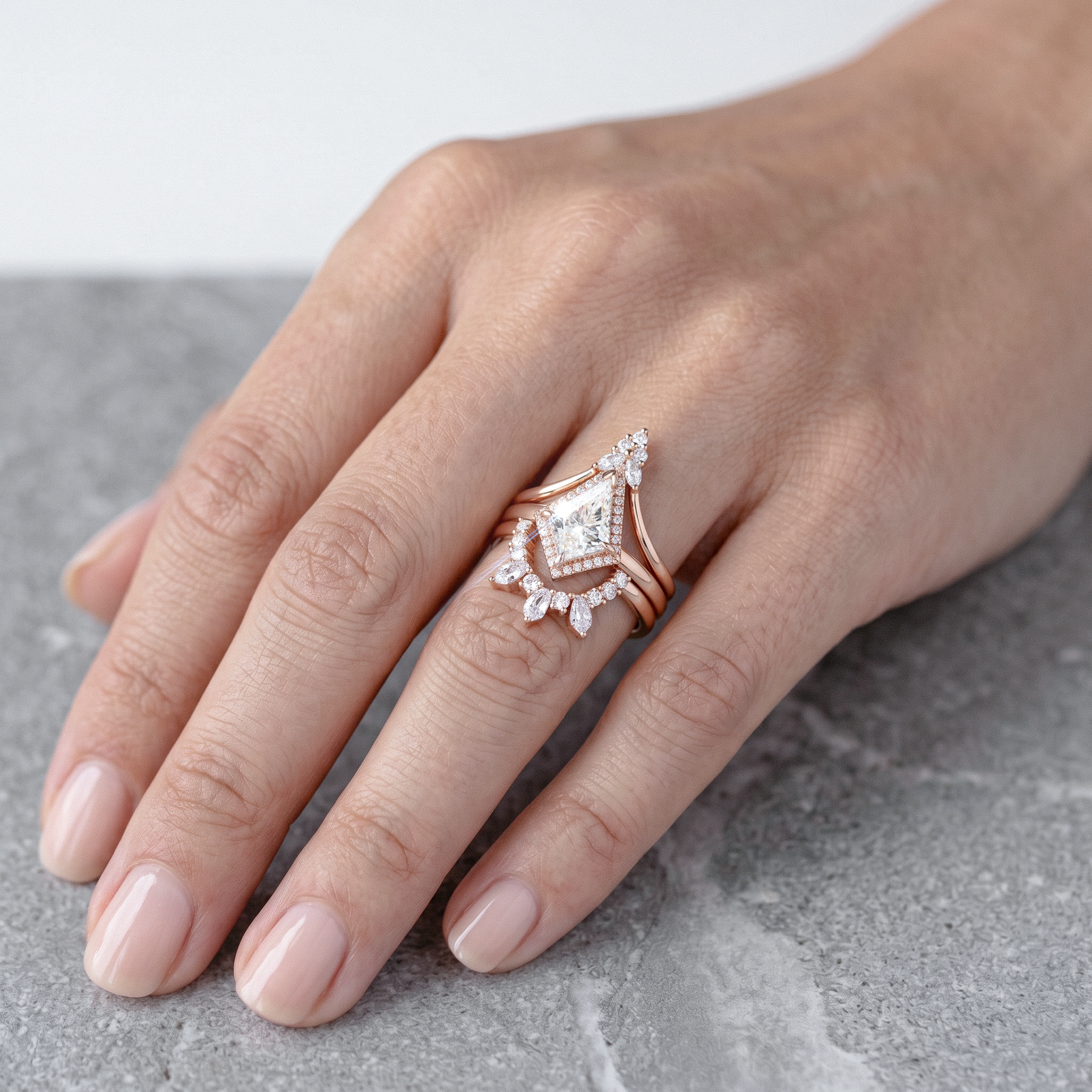 Hand wearing kite shape diamond ring set 3pcs on a gray surface