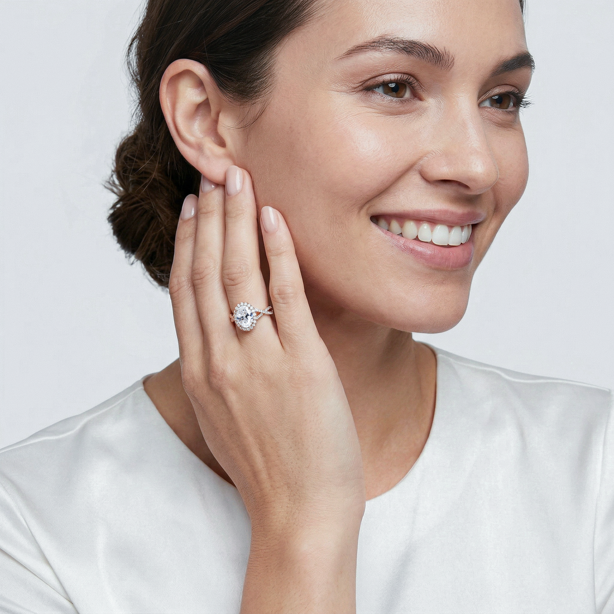 Woman wearing a twisted oval diamond ring on her hand, with a plain background