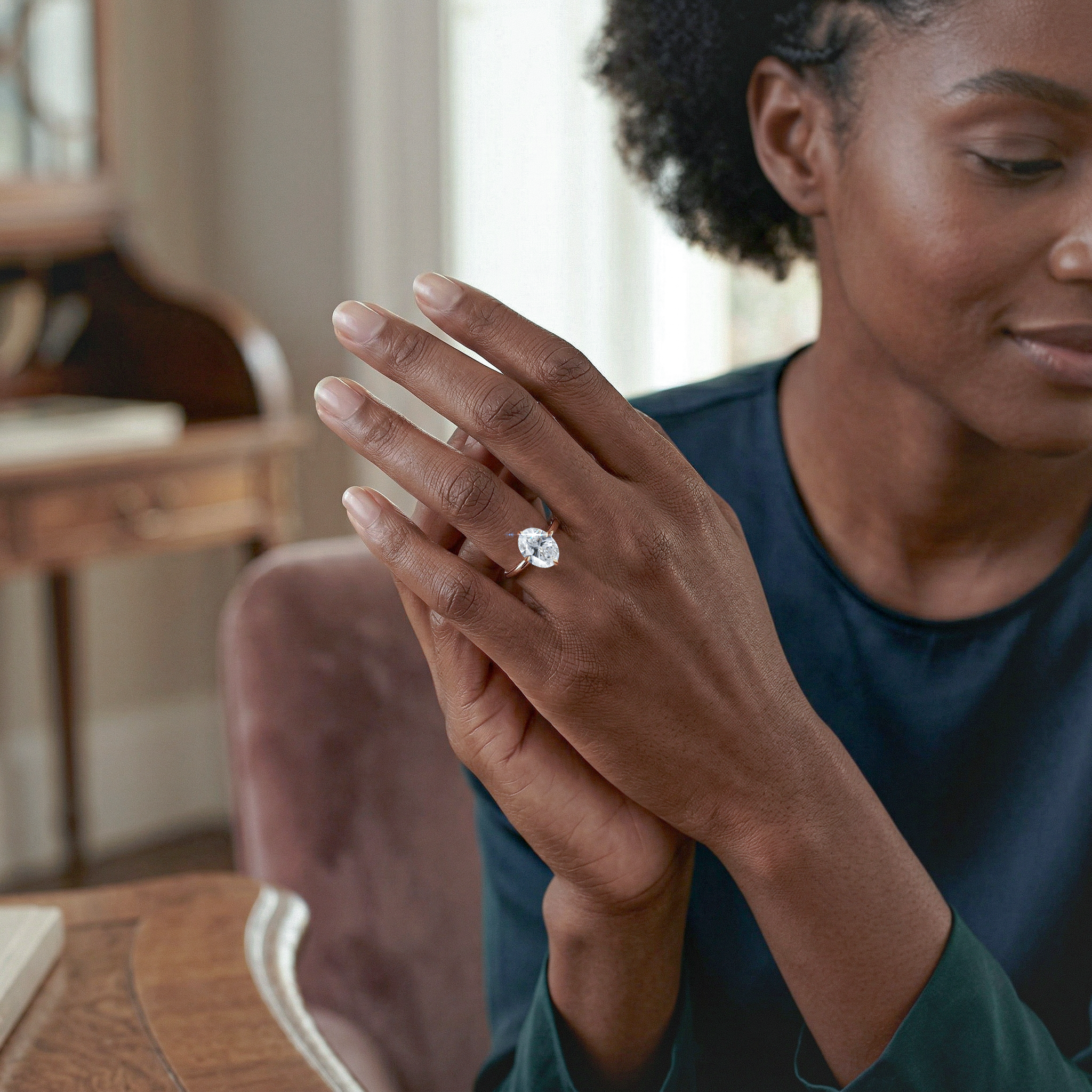 Woman wearing a oval diamond ring in a cozy indoor setting