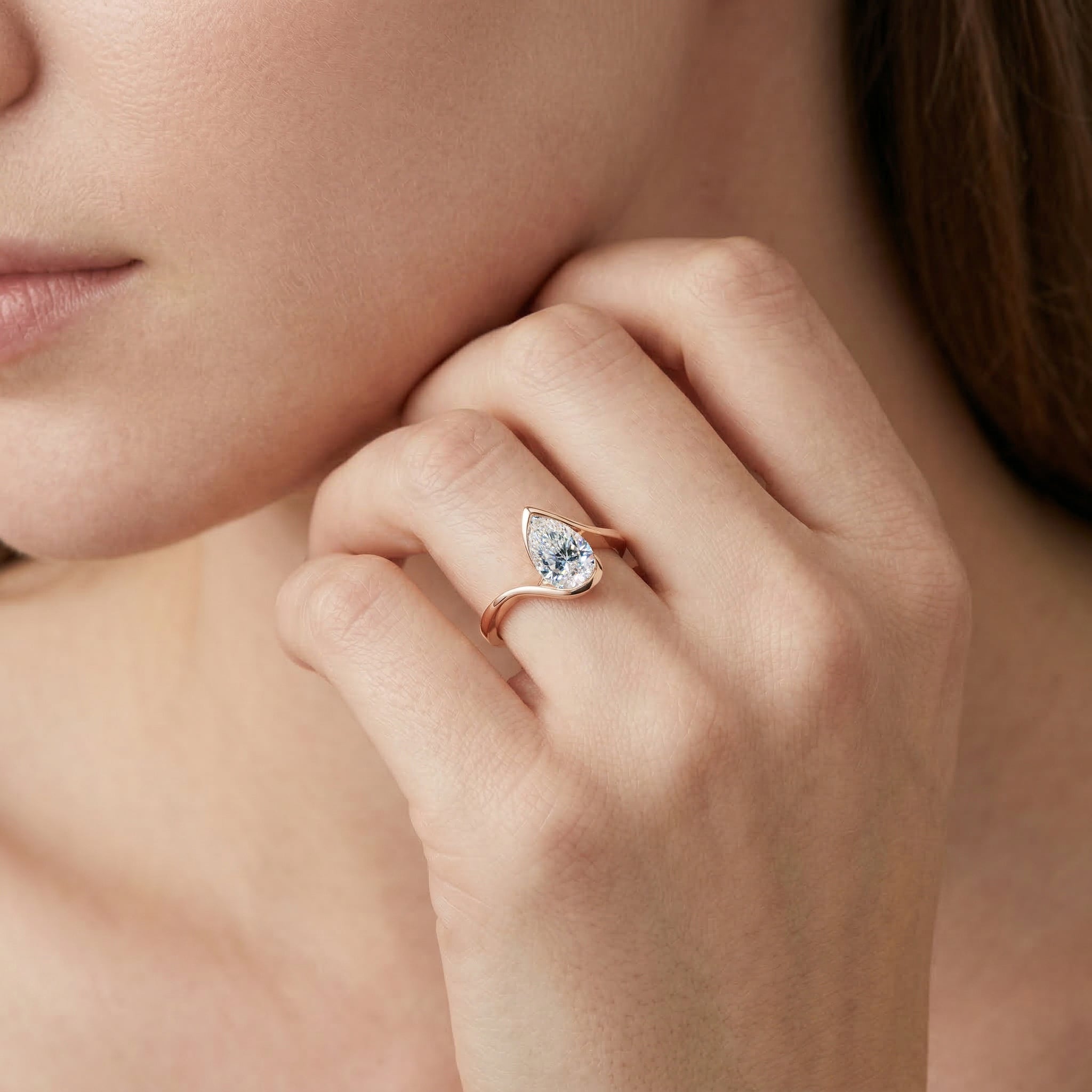 Close-up of a hand wearing a pear cut diamond ring with 