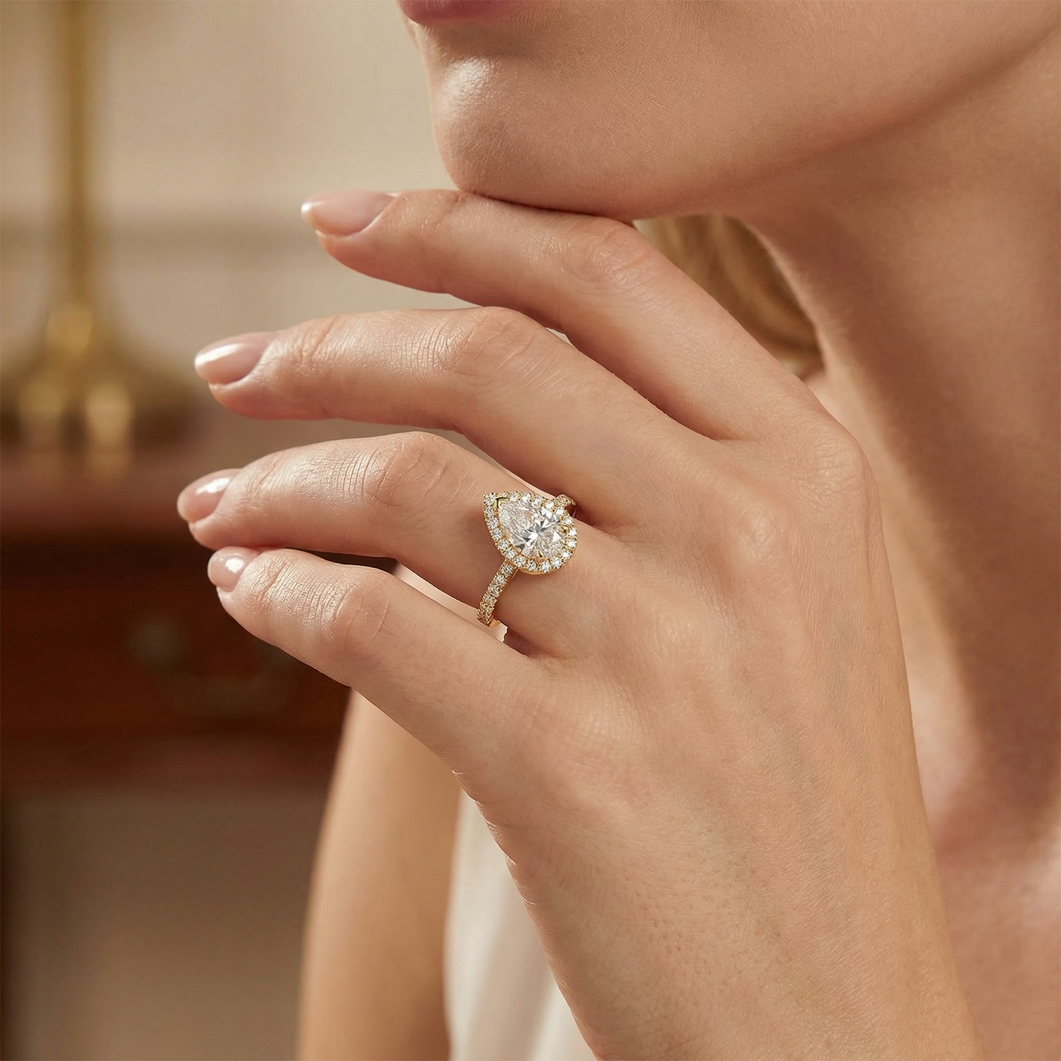 Close-up of a hand wearing a pear shape diamond ring with halo 