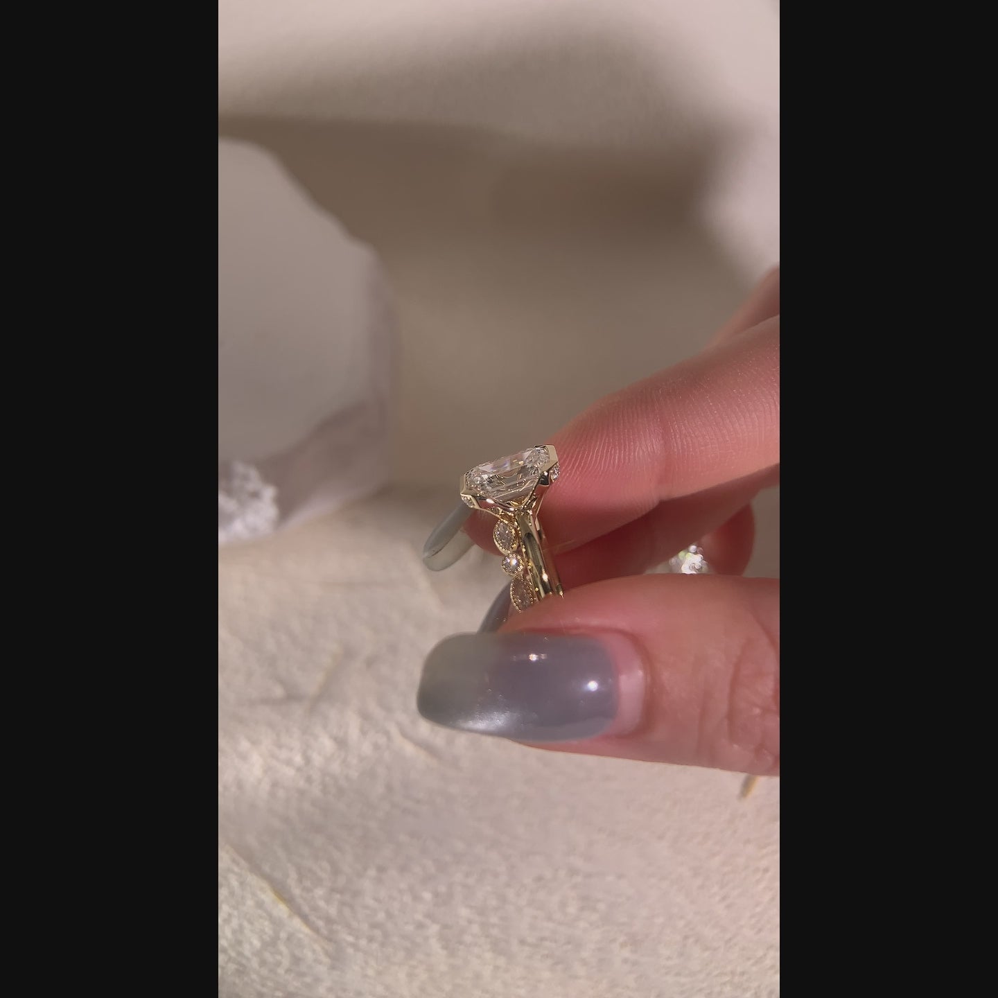 Model wearing an emerald-cut two-ring bridal set with a vintage-style stone band.